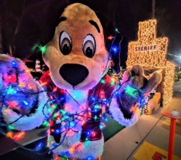 Fiesta Village mascot holding Christmas lights